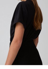 T-shirt nera con maniche arrotolate, caratterizzata da una vestibilità comoda. Il materiale sembra liscio con una finitura opaca. Design semplice e versatile.
