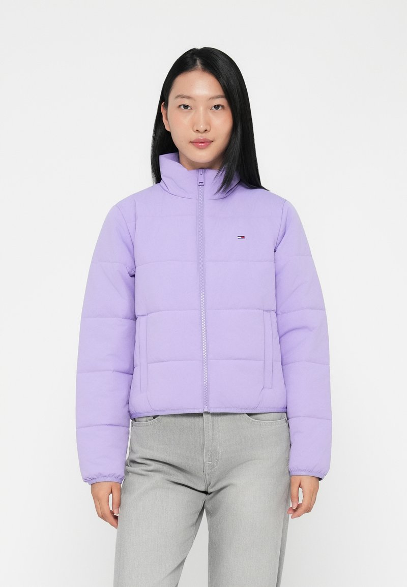 Giacca piumino lavanda con colletto alto, chiusura con zip e un piccolo logo sul lato sinistro del petto. Presenta un design trapuntato e polsini elasticizzati.