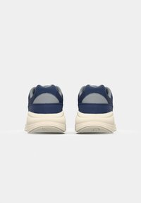 Navy blue sneaker with light gray accents, padded collar, textured sole, rounded design, and visible seams on a clean background.