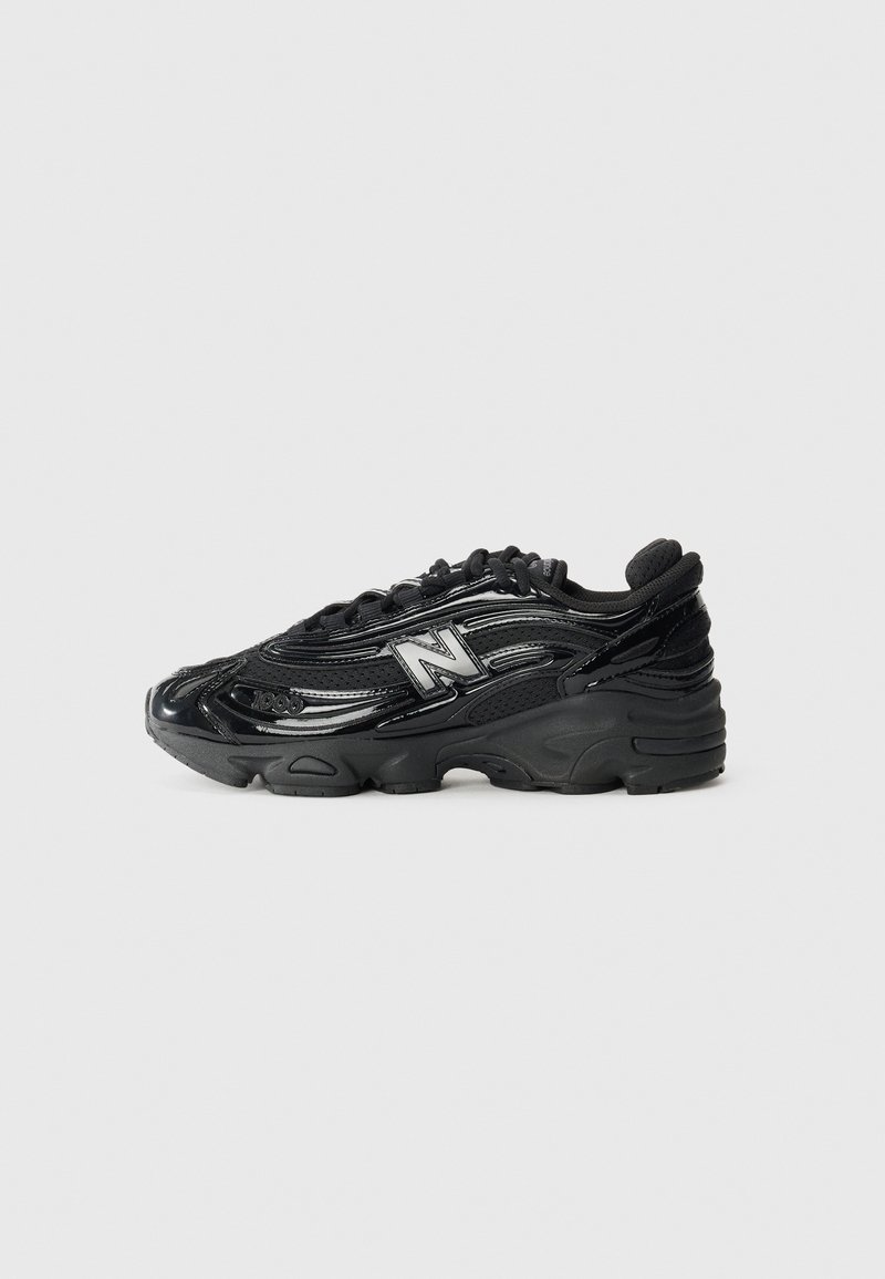 Black running shoe with glossy leather and mesh upper, prominent New Balance logo, thick rubber sole, and textured detailing.