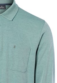 Light green polo shirt with patterned collar, chest pocket, and small embroidered leaf logo on pocket, displayed on white background.