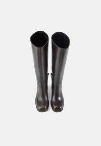 Barna bőr térd fölé érő csizmák sima felületűek, négyzetes orrúak és oldalsó cipzárral rendelkeznek. A belső rész puha béléssel készült.