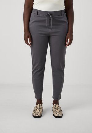 Graue, schmal zulaufende Hosen mit einem Kordelzugbund, glatter Textur und schlanker Passform, kombiniert mit Schuhen im Schlangenlederdesign.