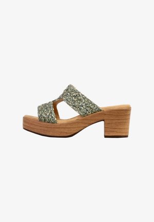 Sandal med åben tå, chunky træsål og flettede metalliske sølvstropper, der krydser over foden.