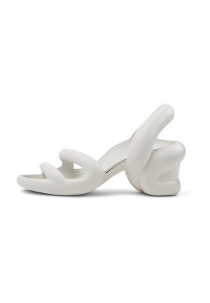 White heeled sandals with a unique, sculptural design. Features two curved straps and a chunky, textured heel. Smooth, matte finish.