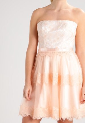 Strapless jurk met een kanten lijfje en een gelaagde perzikkleurige tule rok met kanten rand aan de zoom. Over het geheel lichte, gestructureerde stof.