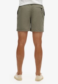 Pantaloni da bagno khaki realizzati in un materiale leggero e ad asciugatura rapida, dotati di tasche laterali con zip e una vestibilità comoda, che si fermano appena sopra il ginocchio.