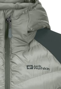 Giubbotto imbottito verde chiaro con texture trapuntata, dotato di zip frontale, pannello spalla in grigio scuro a contrasto e logo Jack Wolfskin.
