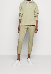 Ljusgrön hoodie med dragsko, ribbade ärmslut och fåll. I kombination med ljusgröna slim-fit byxor och vita sneakers. Minimalistisk design.