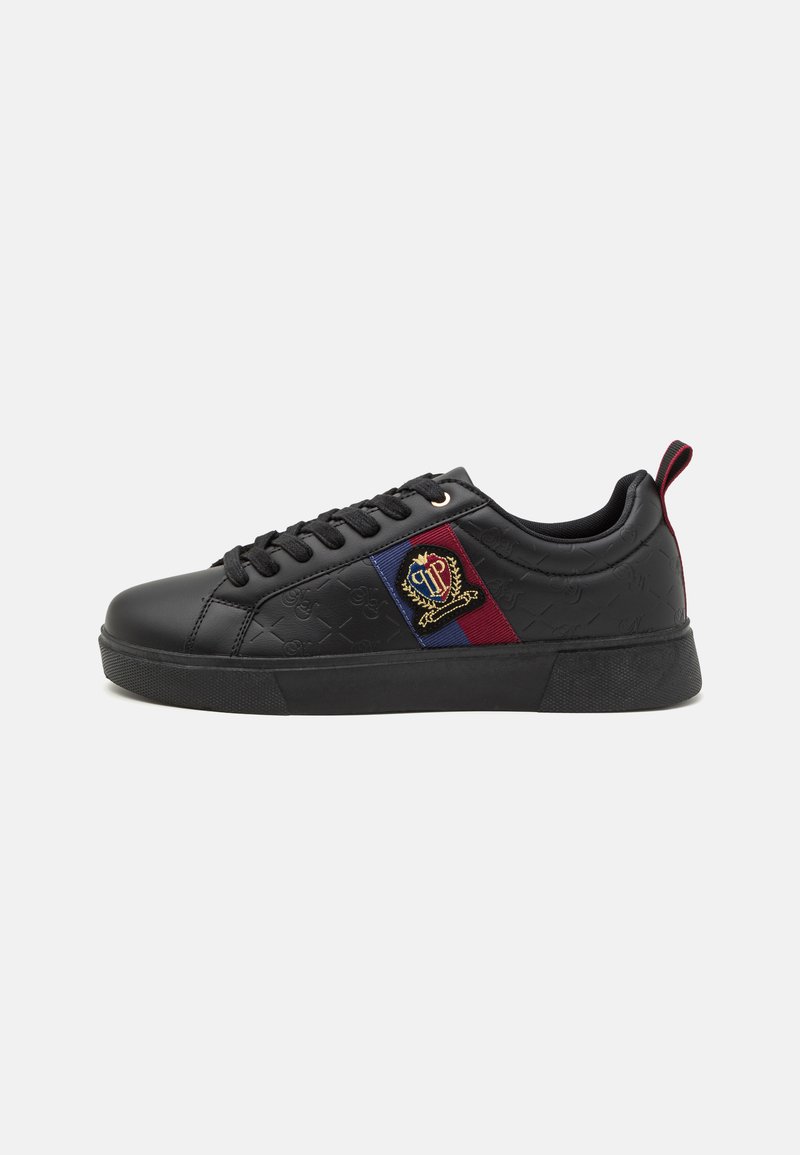 Black sneaker with textured synthetic upper, flat laces, side panel featuring red and blue accents, and embroidered logo detail. Rubber sole.