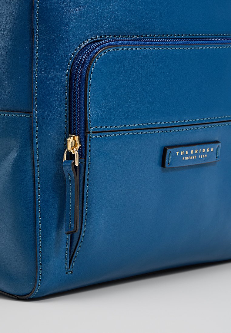 Borsa in pelle blu con tasca con zip, accessori dorati e targhetta del marchio. Texture liscia con dettagli di cucitura ben rifiniti.
