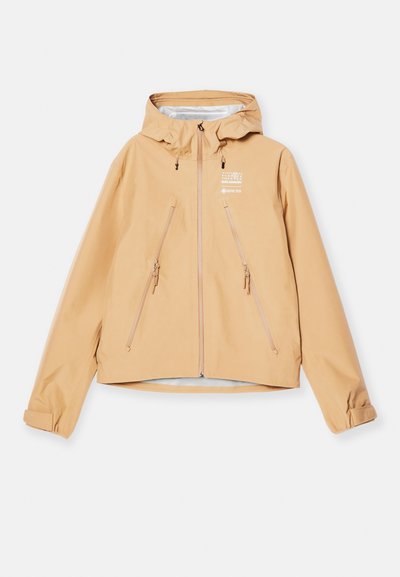 Veste imperméable beige avec capuche, dotée de deux poches zippées, de poignets élastiques et d'une marque subtile sur le côté gauche.