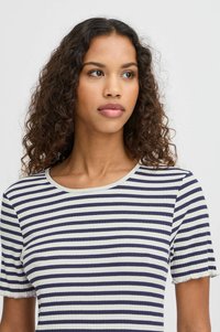 Stribet T-shirt i marineblå og creme, ribbet tekstur, korte ærmer med bølgede kanter, rund halsudskæring, tætsiddende design.