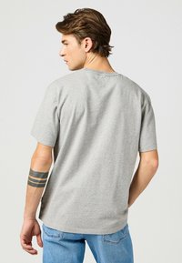 Camiseta de algodón de manga corta en color gris, con cuello redondo y un corte holgado, con textura suave y un diseño minimalista.