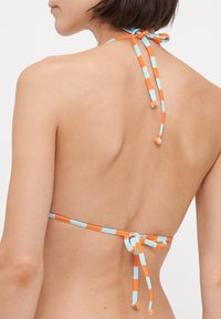 Bikiniöverdel med halterdesign; har orange och ljusblå randiga band. Mjuk tyg, minimal täckning och en säker knut bak.