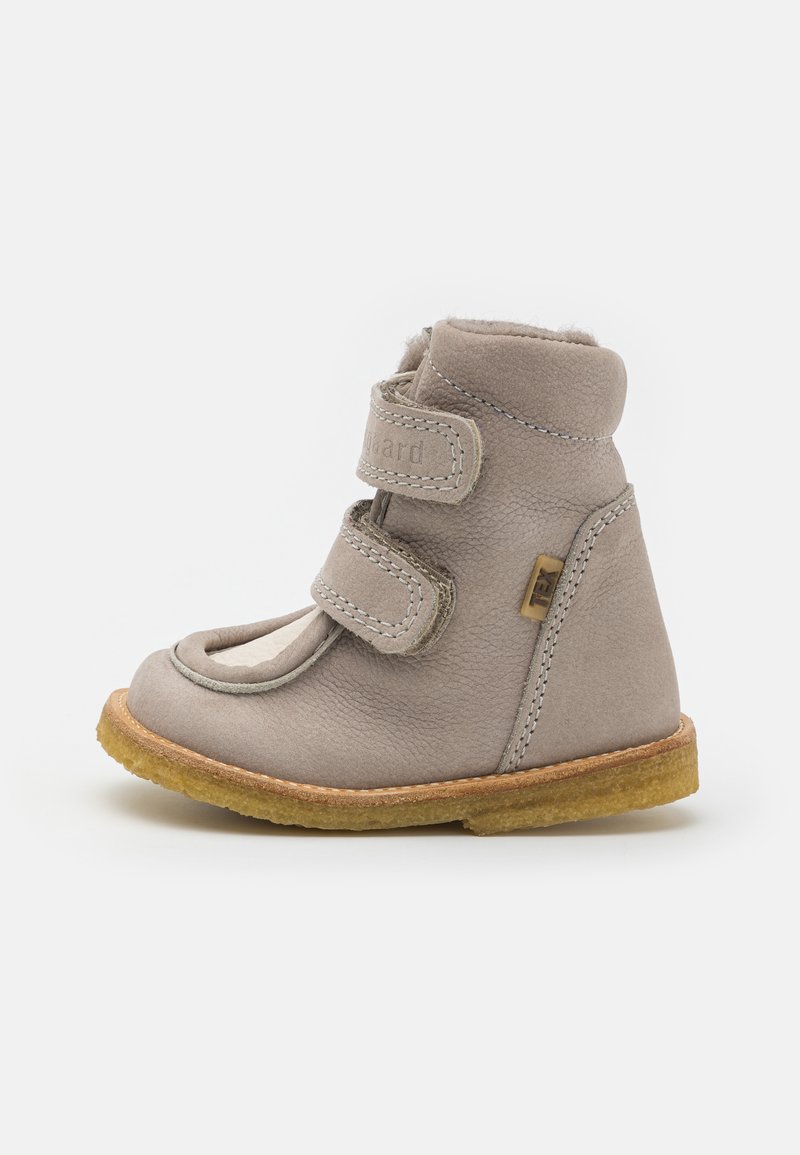 Bottine en cuir gris avec deux bandes Velcro, doublure douce, bout rond et semelle en caoutchouc. Couture notable et détail de logo sur le côté.