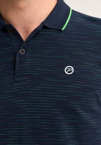 Camisa polo en color navy con un patrón texturizado de franjas horizontales en verde y azul claro. Cuenta con un cuello de dos botones y un pequeño logo en el pecho.