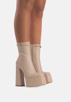 Stivaletti alla caviglia in finta pelle beige con finitura liscia, tacco alto a blocco, zip laterali e un design con piattaforma elevata.