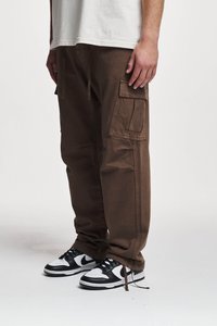 Pantaloni cargo marroni con molte tasche, vita con cordino e vestibilità comoda, abbinati a sneaker nere e bianche. Tessuto testurizzato.