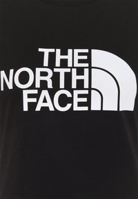 Svart t-shirt med stor vit text som säger "THE NORTH FACE." Tyget har en mjuk textur och standard rundhaldesign.