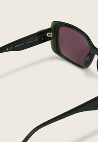Groene acetaatsonnenbril met een vierkant montuur, donkerroze lenzen en goudkleurige hardware op de scharnier. Bandlengte: 140 mm, lensbreedte: 54 mm.
