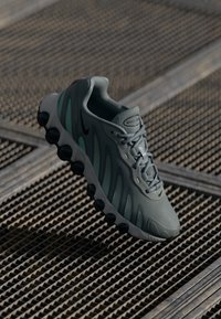Nike sneakers in gray with a textured upper, mesh accents, and black outsole. Features a sleek design with subtle branding details.
