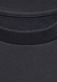 Temno siva pletenina z rebrastim ovratnikom, ki prikazuje gladko teksturo in enakomerno šivane, z diskretnim mrežnim vzorcem spodaj.