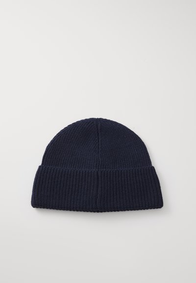 Marineblaue gestrickte Mütze mit Rippenstruktur, ausgestattet mit einem umgeschlagenen Saum und einem auffälligen Obernahtdetail. Weiches Material geeignet für kaltes Wetter.