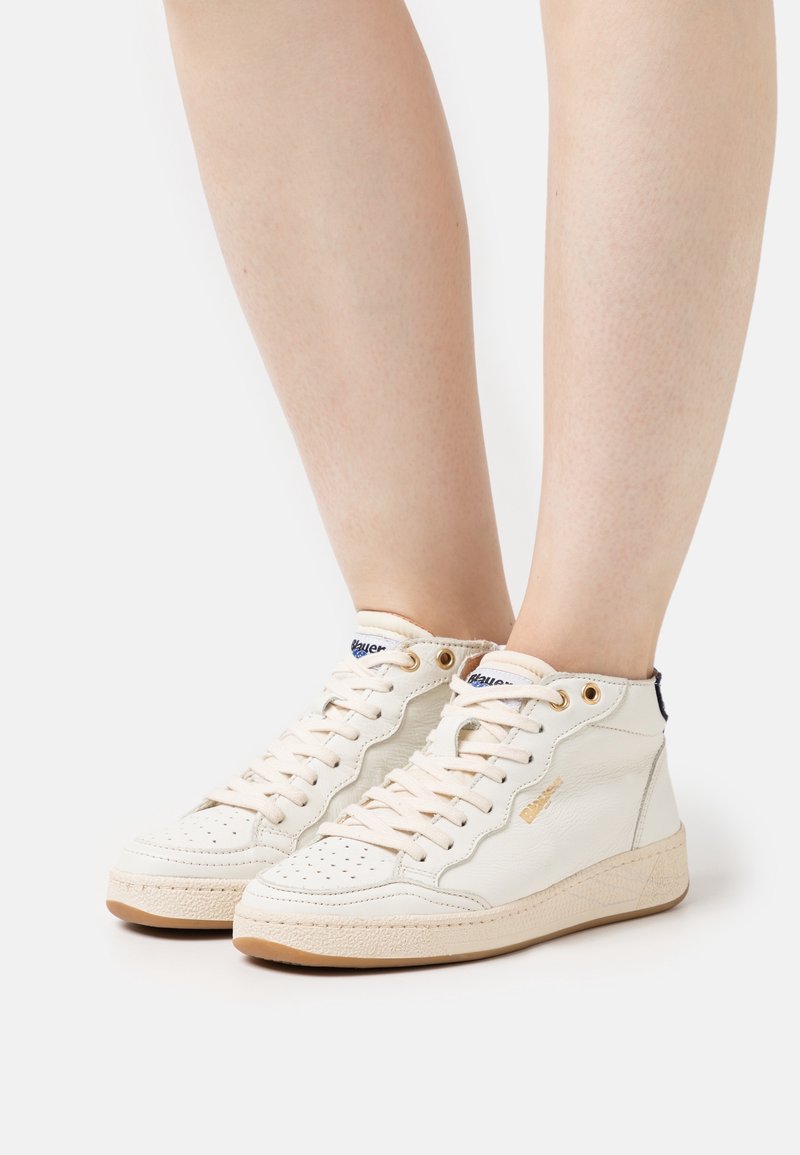 Cremfarbene Leder-High-Top-Sneaker mit durchbrochenem Zehenbereich, goldenen Ösen und beige-gummierter Sohle, ausgestattet mit einem marineblauen und goldenen Logo-Tag auf der Zunge.