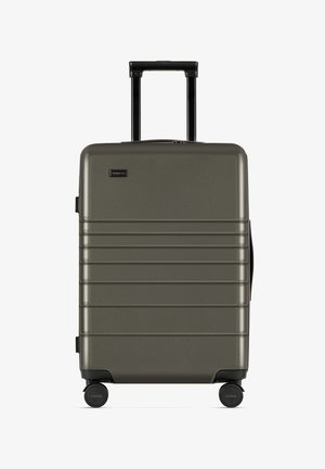 Twarda walizka w oliwkowym kolorze, z rowkowanym wzorem, czarnym uchwytem i czterema kółkami zapewniającymi łatwość w poruszaniu się.