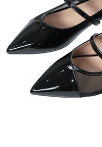 Ballerine nere a punta con materiale lucido in vernice e pannelli in rete. Presentano due fasce incrociate, superficie liscia e texture a contrasto.