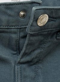 Temno turkizna denim tkanina z gladko teksturo, ki vključuje kovinski gumb za zapiranje in vidne detajle šivanja. Poglobljen pogled na pas.