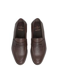 Par de mocasines de piel de cuero texturizado marrón oscuro con punta redonda y plantillas negras con la marca, mostrados desde arriba sobre un fondo blanco.