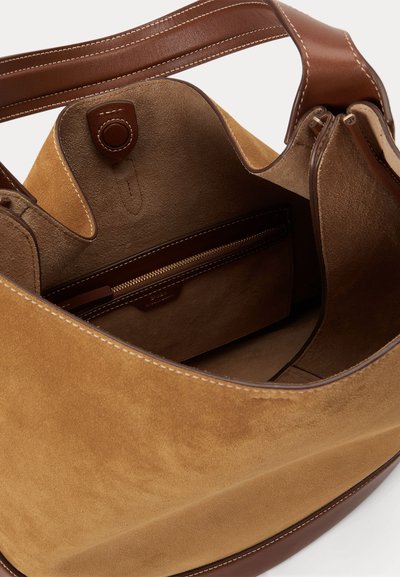 Sac à main en daim beige et cuir marron avec une large bandoulière, ouverture sur le dessus et poche intérieure zippée avec détail bouton.