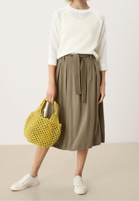 Lekki biały sweter dzianinowy z rękawami do połowy łokcia, zestawiony z oliwkowozieloną spódnicą do kolan oraz żółtą plecioną torbą. Białe trampki.