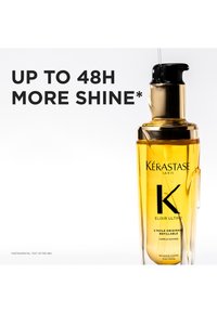Kérastase Elixir Ultime haarolie in een transparante fles met een goudgeel vloeistof. Voorzien van een zwarte pomp en gouden accenten.