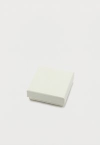 Κλειστό μικρό λευκό χαρτόκουτο σε σχήμα τετραγώνου με υφή στην επιφάνεια, τοποθετημένο σε απλό λευκό φόντο.