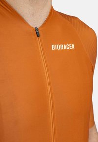 Bioracer fietsjersey in oranje, met een korte rits, een soepele textuur en zijaccenten met patroon voor een verbeterde stijl en ventilatie.