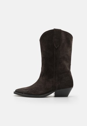 Botte western en daim noir mi-mollet avec bout pointu, talon empilé et bride de traction sur la tige, vue de côté sur fond blanc.