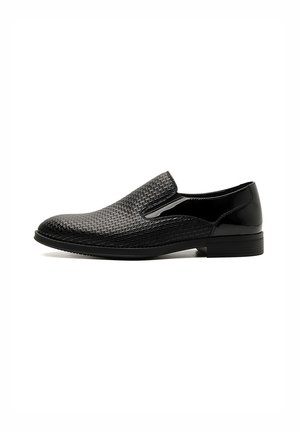 Scarpe slip-on nere con una texture intrecciata sulla parte superiore, dettagli in pelle lucida e una suola in gomma piatta per trazione e comfort.