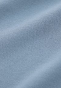 Tela de color azul claro con una textura suave y un sutil patrón de tejido, mostrando un leve drapeado y pliegues en el material.