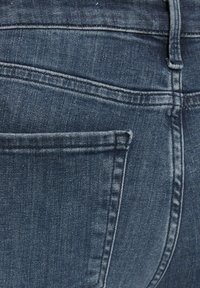 Traperice tamnoplave boje s izblijedjelom teksturom. Imaju stražnji džep s prošivenim rubovima i glatkom završnom obradom.