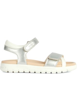 Sandalias metálicas plateadas con una correa de Velcro ajustable, acentos en blanco y suela de goma texturizada. Diseño elegante y estilo de punta abierta.