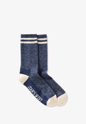 Paar marineblauwe geribbelde sokken met witte tenen, hielen, twee witte strepen bij de boorden en "JEANS WEST" bedrukt op de zool.