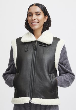 Zwart leren vest met wit schapenvacht kraag en bies, voorzien van een voorrits, zijzakken en zwarte hardware accenten.