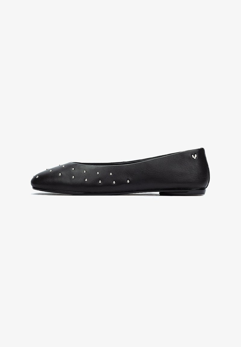 Bailarinas de cuero negro con punta afilada, con adornos de tachuelas plateadas a lo largo del empeine y un pequeño logotipo en el talón.
