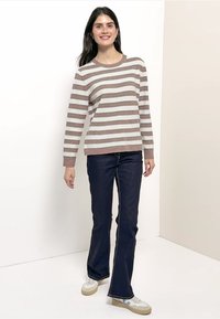 Raitapusero ruskeana ja vaaleanharmaana, neulottu pinta, pyöreä kaula-aukko. Yhdistetty tummansinisiin liehuhousuihin ja lenkkareihin.