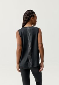 Czarny sportowy top na ramiączkach z plecakiem, z teksturowanym wzorem wzdłuż kręgosłupa. Materiał wydaje się gładki i elastyczny.