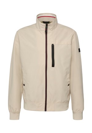 Beige Reißverschlussjacke mit Stehkragen, schwarzem vertikalem Reißverschluss an der Brusttasche, Seitentaschen mit Druckknöpfen und Ärmelbündchen.