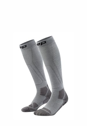 Pair of gray knee-high compression socks with reinforced heel, toe, and arch support areas, featuring black logo near the top.